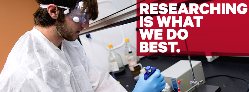 student in the lab wearing googles and protective gear with a pipette syringe