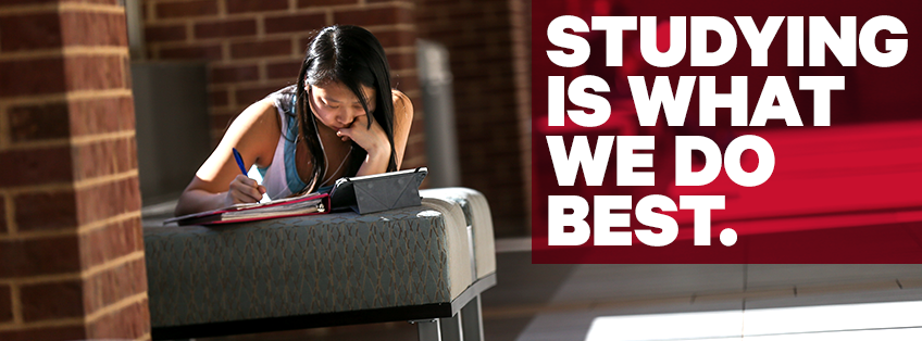 a student lying on her stomach with her books open in front of her working, featuring the text "Studying is what we do best"