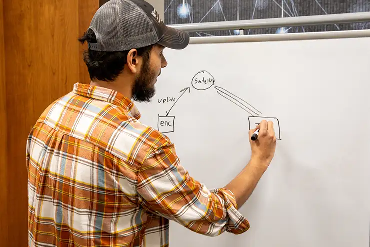 Sartaj Chowdury writing on a markerboard in the cybersecurity capstone course at SEMO.